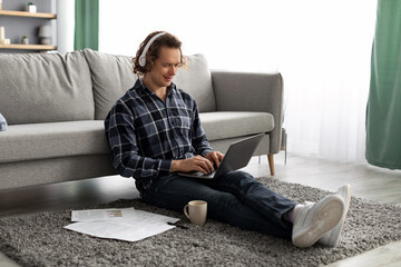 Poster - Happy Man Working On Laptop Wearing Headphones Sitting At Home