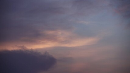 Clouds move in the sky at dusk.