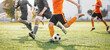 Group of Football Players Running and Kicking League Match. Adult Football Players Compete in Soccer Game. Soccer Stadium in the Blurred Background