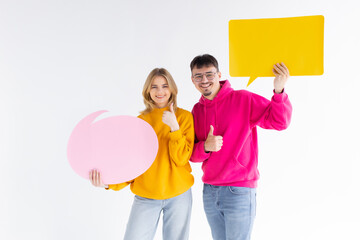 Beautiful young couple is holding speech bubbles and smiling, on white background