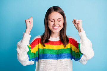 Sticker - Photo of lucky charming young lady wear striped outfit rising fists closed eyes isolated blue color background