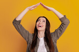 Fototapeta Nowy Jork - Photo of young surprised girl hold arms roof isolated on yellow background