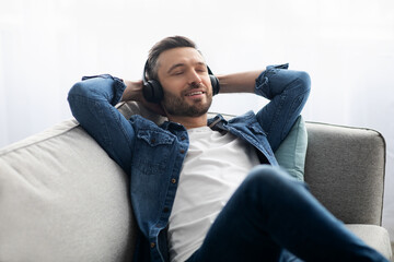 Wall Mural - Joyful middle-aged man in headphones listening to music