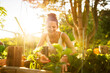 © Annika List/Westend61 - Young woman picking up strawberries in garden at sunrise