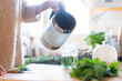 © Annika List/Westend61 - Woman's hand pouring water in jar to prepare tea in kitchen