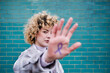© Angel Santana Garcia/Westend61 - Curly haired woman showing colon cancer ribbon symbol on hand