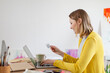 © Emma Innocenti/Westend61 - Smiling woman paying with credit card from laptop at home studio