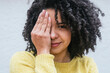 © MORNINGVIEW AGENCY/Westend61 - Curly haired woman covering eye against white wall