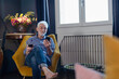 © Emma Innocenti/Westend61 - Senior man with wineglass using mobile phone while sitting on chair at home