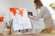 © Emma Innocenti/Westend61 - Female artist taking photo of painting at home studio