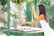 © GER/Westend61 - Woman pulling rope tied to bucket at water well while gardening in backyard