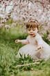 © Gala Mart√≠nez L√≥pez/Westend61 - Baby girl sitting on grass near cherry tree in springtime