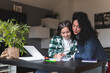 © Josu Acosta/Westend61 - Mother assisting daughter while studying at table in living room