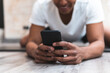 © Josu Acosta/Westend61 - Young man using smart phone on tiled floor at health club