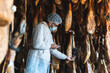 © Josu Acosta/Westend61 - Employee choosing ham hanging in slaughterhouse