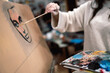 © Jose Carlos Ichiro/Westend61 - Female artist painting face on canvas at art studio