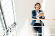 © Joseffson/Westend61 - Happy businesswoman with digital tablet leaning on railing at corridor