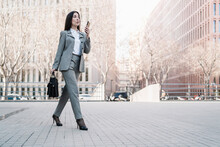 Mature Businesswoman Talking On Smart Phone While Walking In City