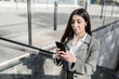 © COROIMAGE/Westend61 - Businesswoman using smart phone while standing on escalator in city