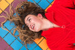 © Julio Rodriguez/Westend61 - Smiling woman looking away while lying down on tiled floor