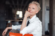 © Robijn Page/Westend61 - Blond businesswoman with hand on chin sitting on chair on loft apartment