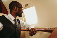 Young businessman looking through window while traveling in airplane