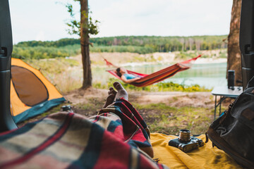 Wall Mural - person view couple resting at camping woman laying in hammock with beautiful view of forest lake