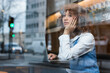 © NOVELLIMAGE/Westend61 - Thoughtful teenage girl sitting with hand on chin by laptop at cafe window
