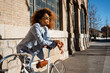 © Rafa Cort√©s/Westend61 - Afro woman in sunglasses leaning on bicycle against building