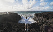 © SERGIO NIEVAS/Westend61 - Male tourist making peace sign while standing on volcanic rock during sunny day at Los Hervideros, Lanzarote, Spain