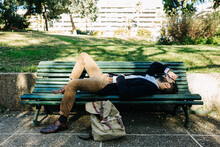 Businessman Resting While Lying On Bench At Park