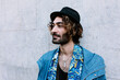 © Xavier Lorenzo/Westend61 - Young man with hat looking sideways in front of wall