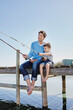 © Roger Richter/Westend61 - Mature man and boy sitting with fishing rods on pier