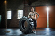 © Roger Richter/Westend61 - Male athlete with hand on hip standing by tire in sports studio