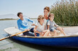 © Roger Richter/Westend61 - Mature man paddling while sitting with family in rowboat on sunny day