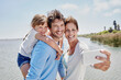 © Roger Richter/Westend61 - Smiling woman taking selfie with family by lake on sunny day
