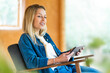 © steve brookland/Westend61 - Smiling woman with digital tablet looking away while sitting on armchair at spacious room