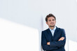 © steve brookland/Westend61 - Mid adult businessman looking away while standing with arms crossed on wall
