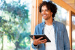 © steve brookland/Westend61 - Smiling young man holding digital tablet while standing by window at front yard