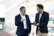 © steve brookland/Westend61 - Business people discussing over digital tablet while standing at office building terrace