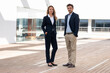 © steve brookland/Westend61 - Confident business people standing with hands in pockets at office building terrace
