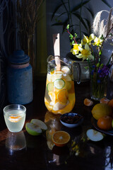 Wall Mural - Fruit healthy lemonade with fresh orange, cucumber, tangerine, lemon, apple and honey in glass jar with  spoon on wooden background in sun light