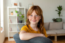 Smiling Redhead Girl With Blue Eyes Sitting On Chair At Home