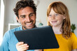 © steve brookland/Westend61 - Redhead girl with father looking at laptop at home