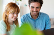 © steve brookland/Westend61 - Smiling redhead girl with laptop e-learning while sitting by father at home