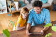 © steve brookland/Westend61 - Smiling father and daughter looking at digital tablet while sitting in living room