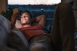 © Uwe Umst√§tter/Westend61 - Smiling young man lying on sofa while using smart phone in living room