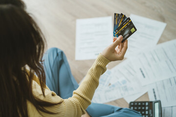 Wall Mural - Top view owe asian woman sitting on floor stressed and confused by calculate expense from invoice, bill of credit card, have no money to pay, mortgage or loan. Debt, bankruptcy or bankruptcy concept.