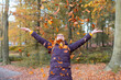 © William Perugini/Westend61 - Cheerful woman playing with autumn leaves in forest