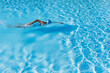 © Gaby Wojciech/Westend61 - Woman swimming in clear blue swimming pool